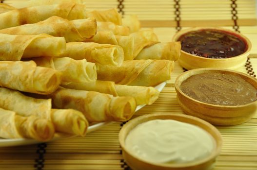 Rolled Pancakes with Cranberry Jam, Chocolate and Sour Cream on Bamboo Placemat