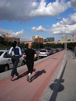 A couple jogging over a cycle line in Madrid.