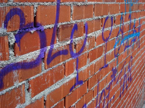 Purple words on an unfinished brick wall.