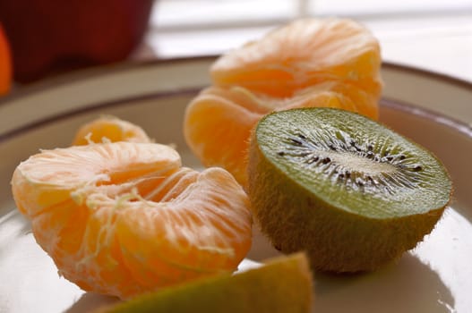 Kiwi and Clementine Tangerines on a plate in early morning light.