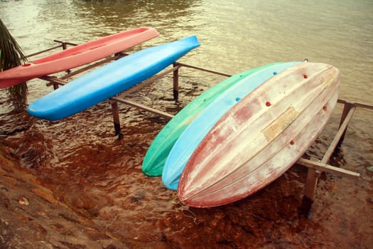 a bunch of plastic canoes for rent on a nearby beach resort
