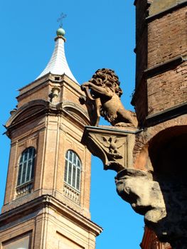 Detail of the lion statue on Asinelli tower and belltower of Saint Bartholomew church in Bologna