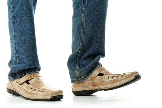 Human foot with brown leather shoes and jeans, isolated on white