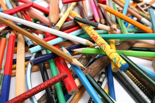 Collection of multi-colour pencils from a tree and plastic on a white table