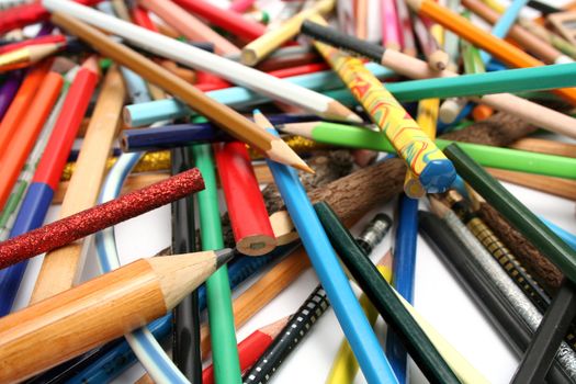 Heap of multi-colour pencils from a tree and plastic on a white table