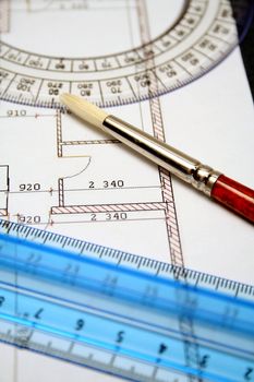 Measuring rulers and art brush on a paper with the plan of the house