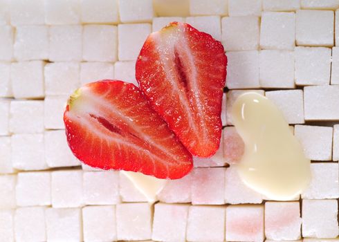 White sugar cubes background with strawberry and milk