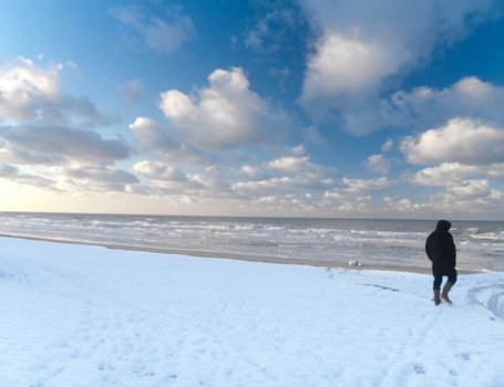 Man walking in snowy beach along the North sea in France