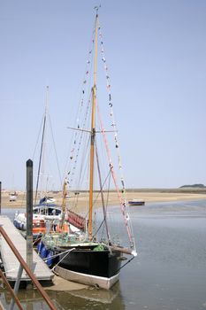 tall boats sitting at the quayside at low tide