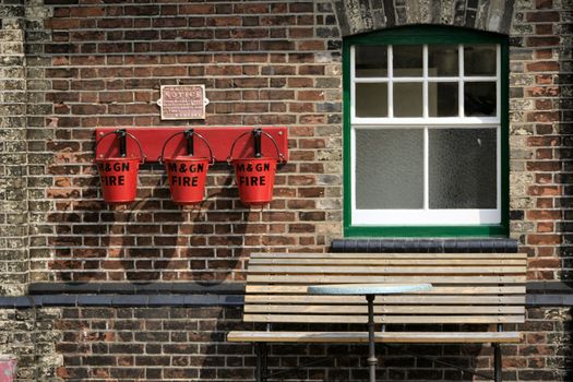 three fire buckets next to a window and bench