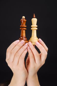 Two hands with black and white chesspieces 