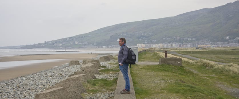 Man looking over an empty beach on a cloudy day.