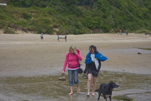 Two pretty girls walking and chatting on the beach