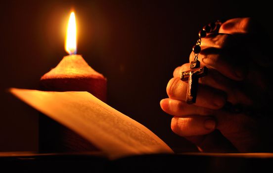 Still life with candle, prayer book and prayer hands