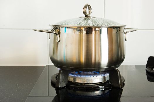 Metal cooking pan on gas burner with burning gas flames