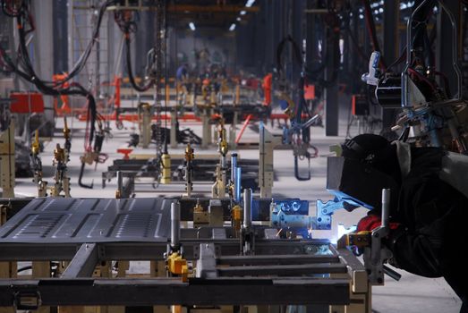 welding operator works with car details on factory