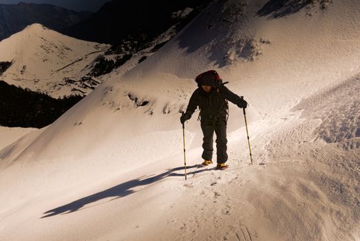 Dramatic scenic of man hiking on sunset mountain path.