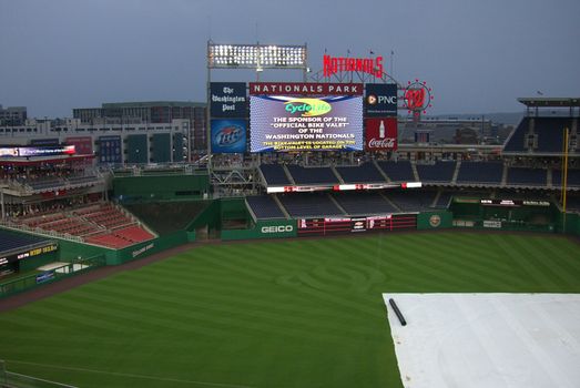 Fans gather under the scoreboard during a rain delay at an early spring Nats baseball game.