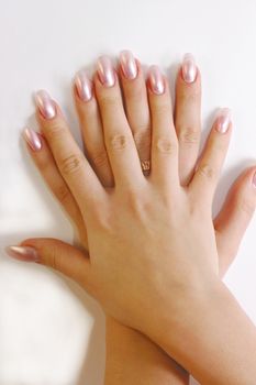 Two woman's hands with manicured nails and gold ring