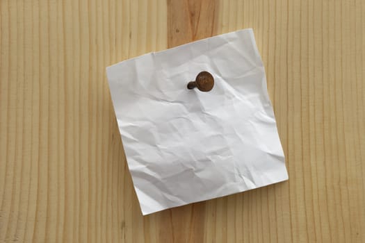 white crumpled blank reminder note nailed to a wooden plank or wall