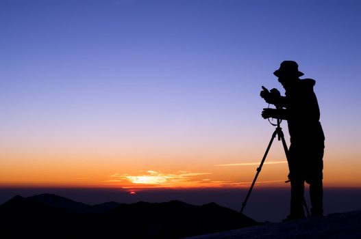 Outdoor photographer silhouette with dramatic color sunrise.
