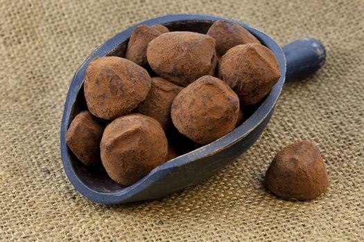 chocolate truffles on a rustic wooden dark painted scoop against burlap background