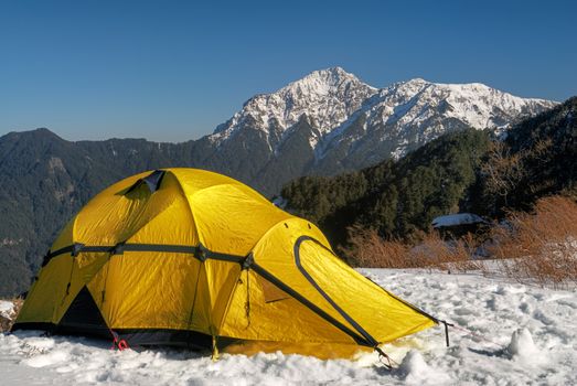 Yellow tent on snow hill in winter.