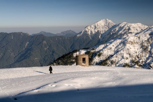 Man walk and blockhouse stand on snow white mountain.