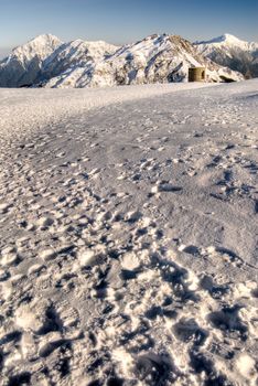 Mountain scenery with messy footprints on snow path in winter.