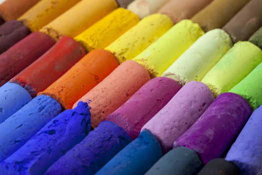 a macro of soft artist pastel crayons with vibrant blue, red, green, yellow colors