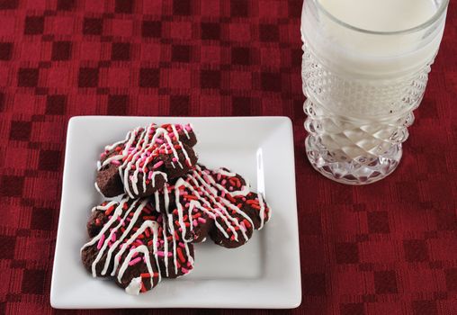 plate of cookies and a glass of milk on a red mat