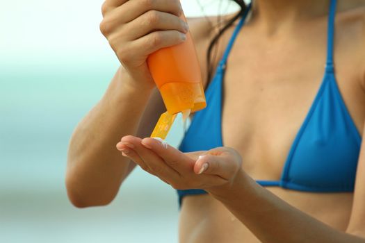 girl on the beach creming body to protect against UV light