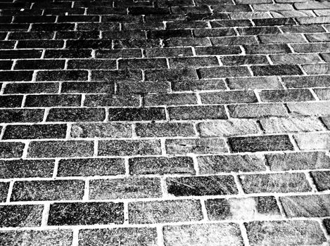 A background black and white photograph of bricks, going from very dark in the top left corner to lighter in the bottom right.