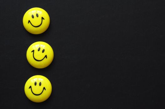 yellow smiley or smilie on black chalkboard with copyspace for a text message