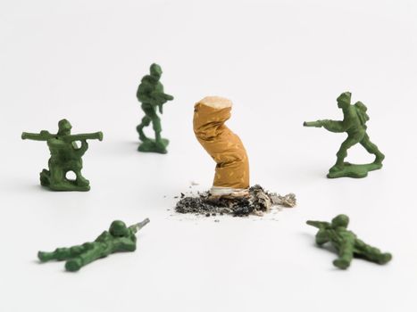 A cigarette butt surrounded by a group of toy soldiers.