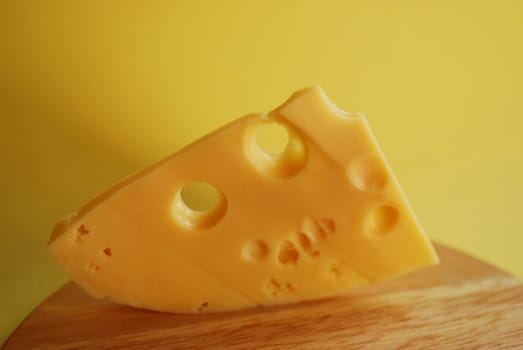 Piece of cheese on a yellow background