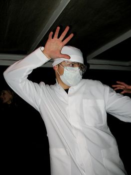Funny dancing doctor in a white robe and a gauze bandage