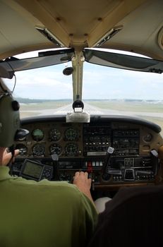 The interior of a small aircraft, with the runway visible out the window.  Landing