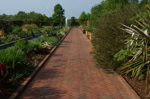 A red brick garden walk with plants in bloom