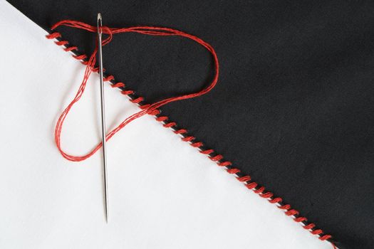 Closeup of black and white textile material jointed by red thread seam