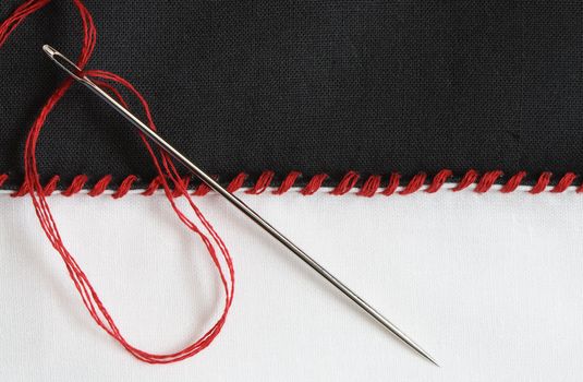 Closeup of black and white textile material jointed by red thread seam