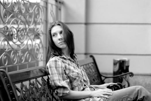 Girl sitting on beanch near fence 
