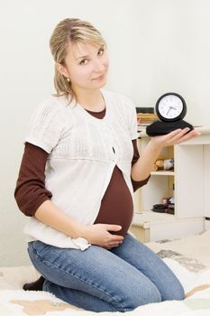 Pregnant woman holding clock, third trimester