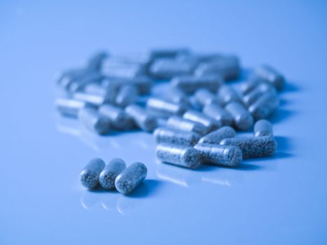 Blue tinted picture of  pills on reflective surface and with selective focus
