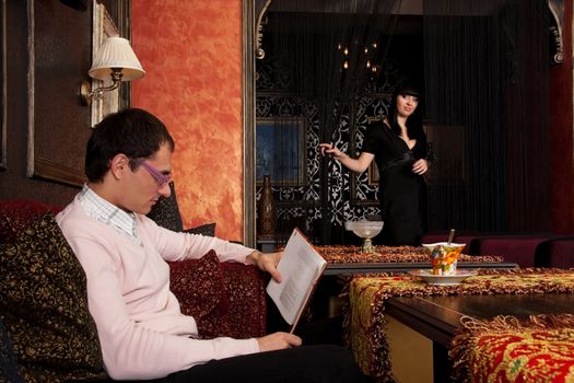 Young couple in luxury interior. He is reading book