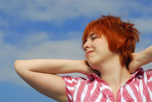Smiling woman with red hair on blue sky background  
