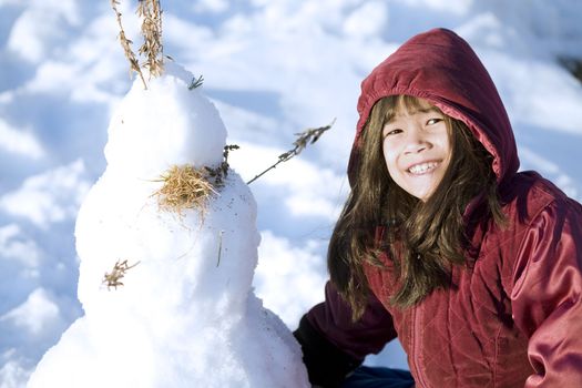 Girl playing in the snow making snowman