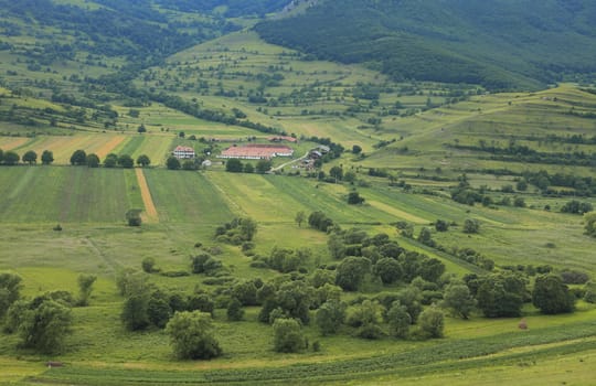 A farm in the middle of beautiful green mountains in summer.Location:Bedeleu Mountains,Transylvania,Romania.