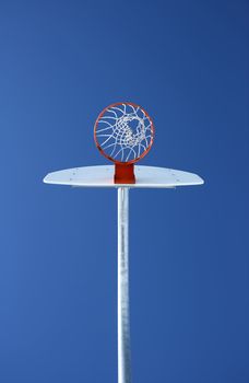Orange basketball hoop against the blue sky, directly from below.