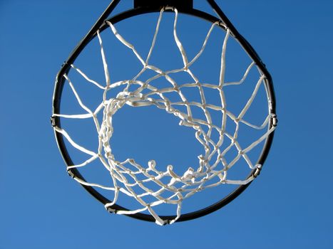 Basketball rim and net against the bright blue sky.